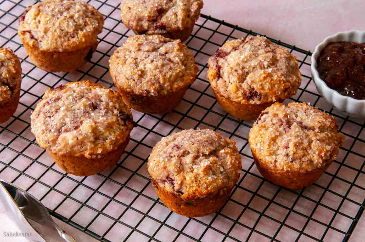 baked muffins on a tray with strawberry preserves on the side.