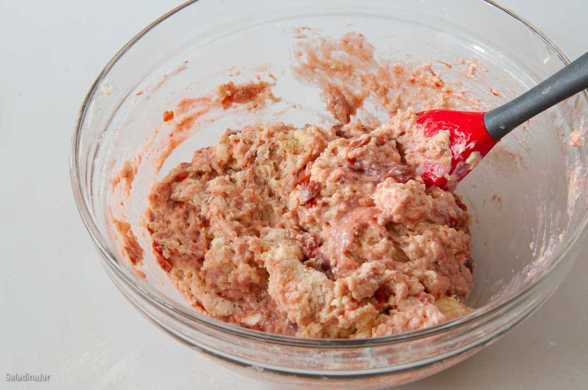 Folding goat cheese and strawberries into the muffin batter.