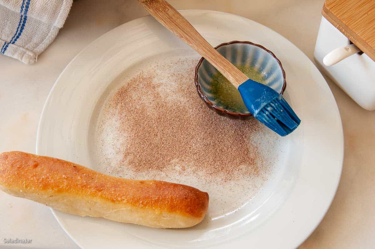baked bread stick on a plate with cinnamon and sugar.