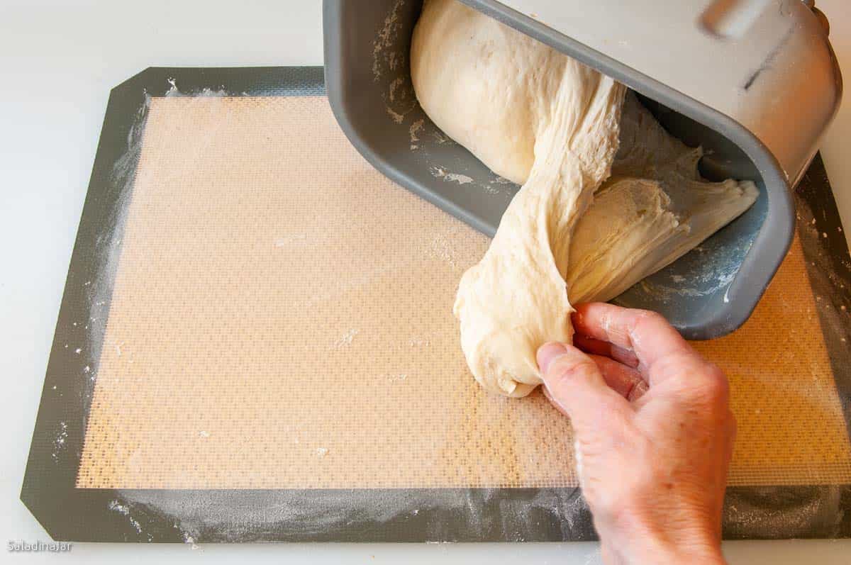 pulling the dough out of the bread machine pan.