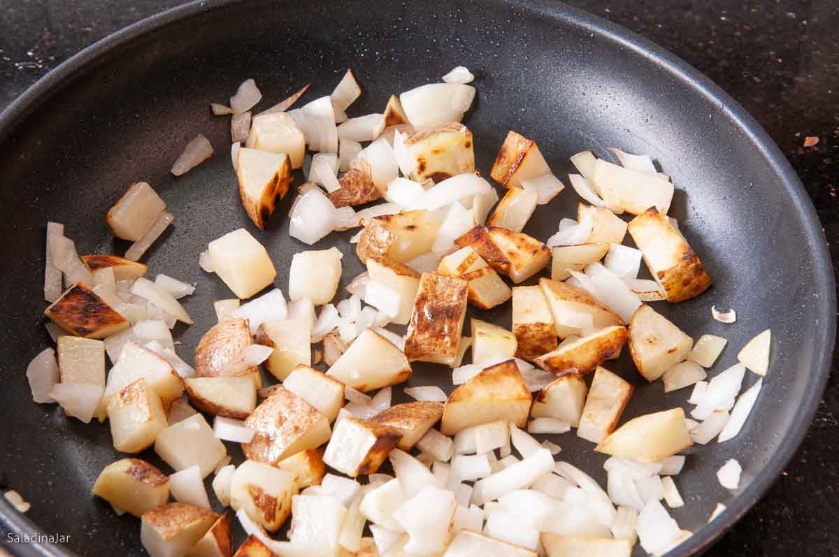 potatoes and onions in a frying pan.