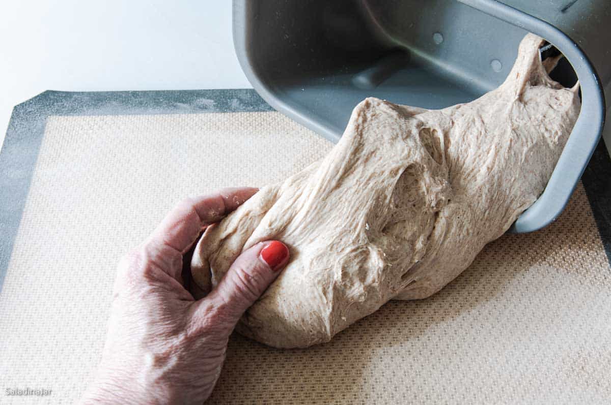 Pulling the dough out of the bread machine pan for the final shaping.