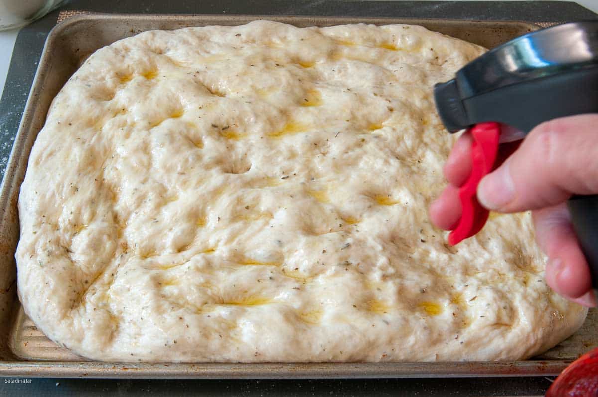 spraying dough with oil before placin in the oven
