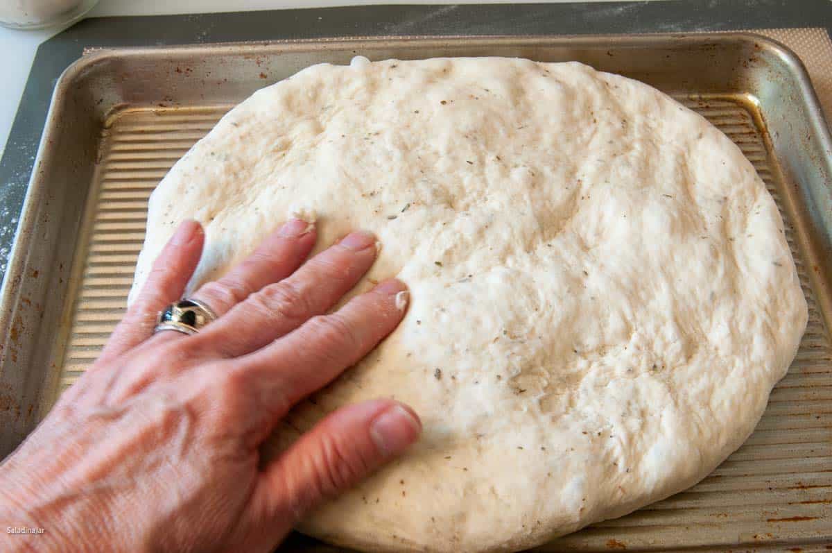 Using hands to spread dough in a greased pan