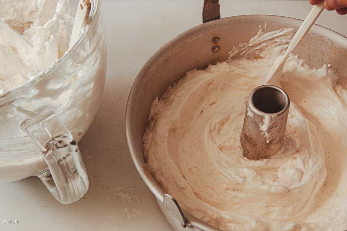 Adding two-thirds of the batter to an angel food cake pan.