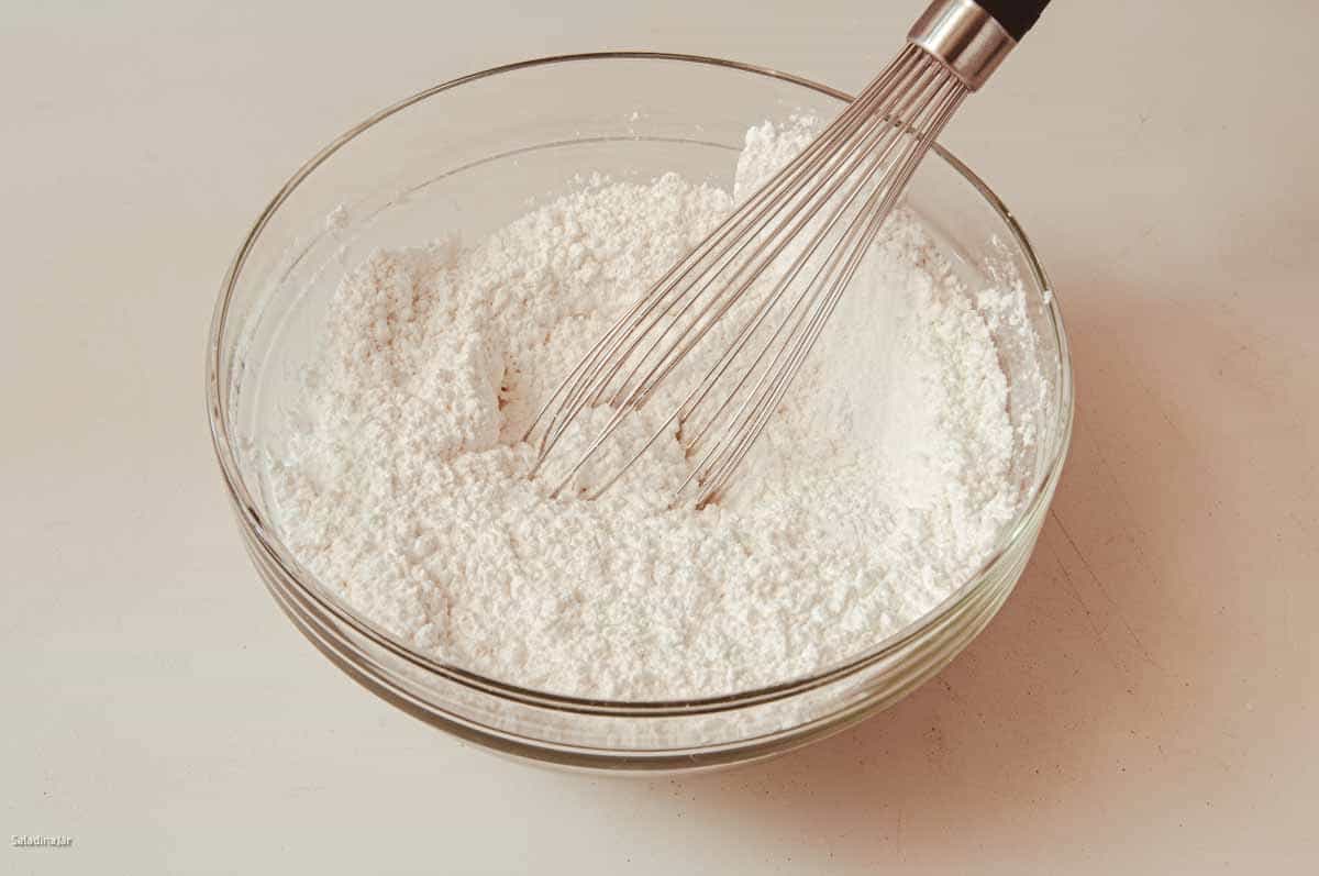 using a whisk to combine the powdered sugar and cake flour
