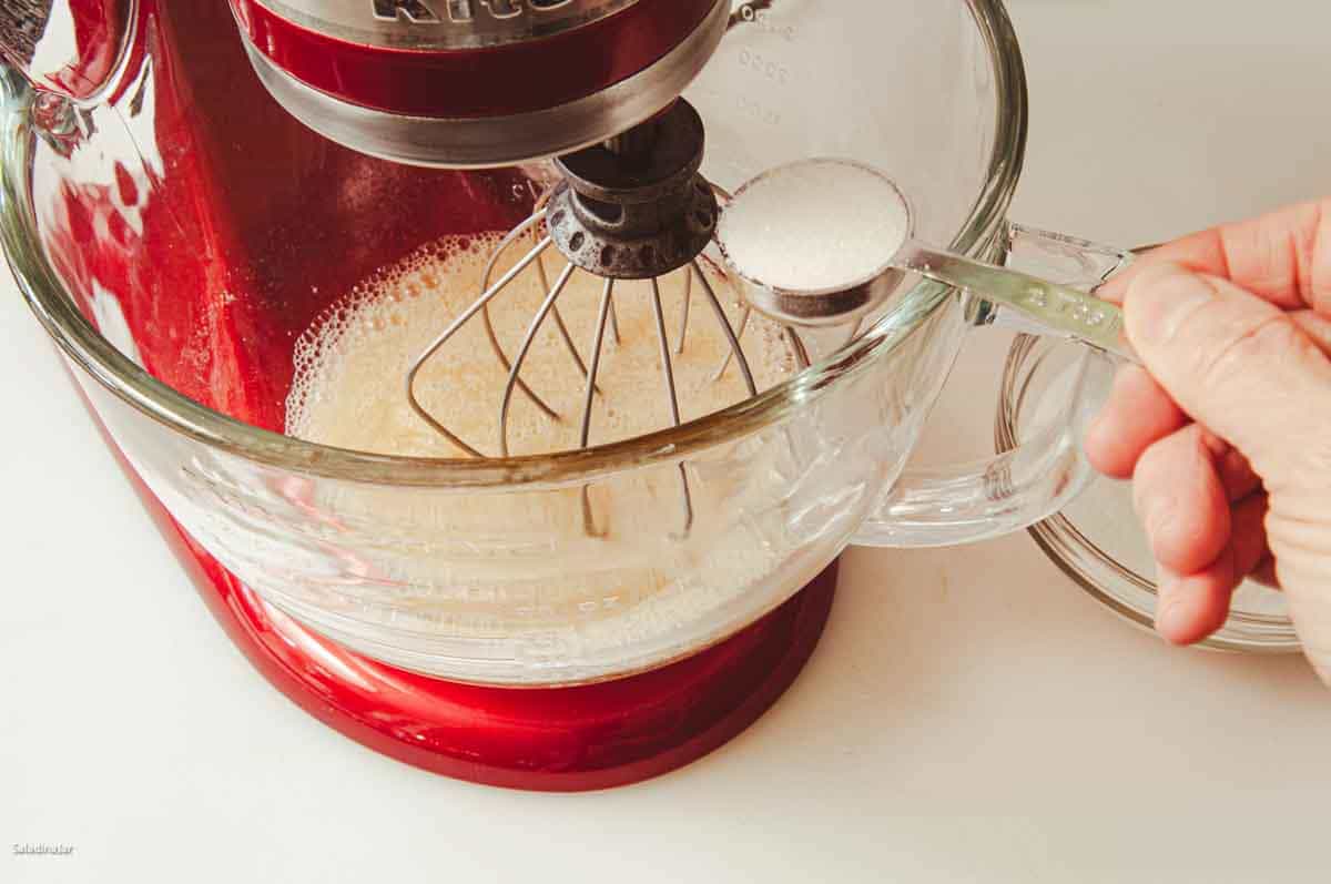 Adding sugar to the egg whites.