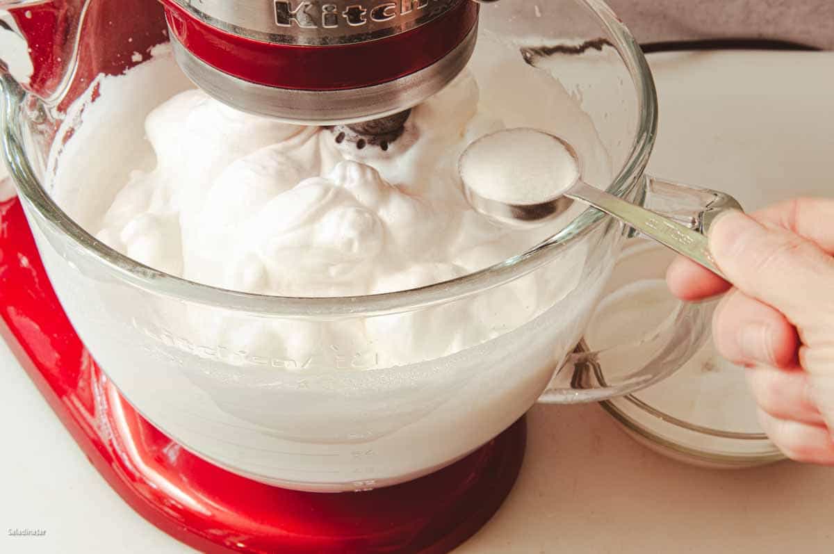 adding the sugar to the egg whites.