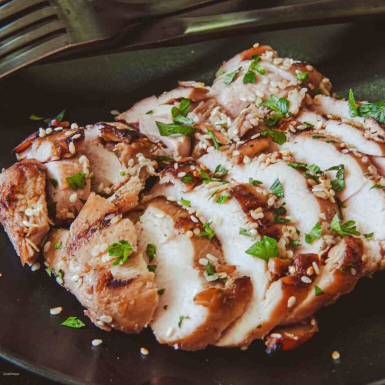 sliced teriyaki chicken thighs ready to eat on a black plate.
