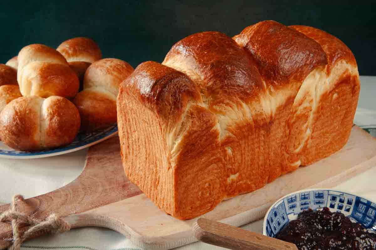 Brioche loaf with rolls in the background.