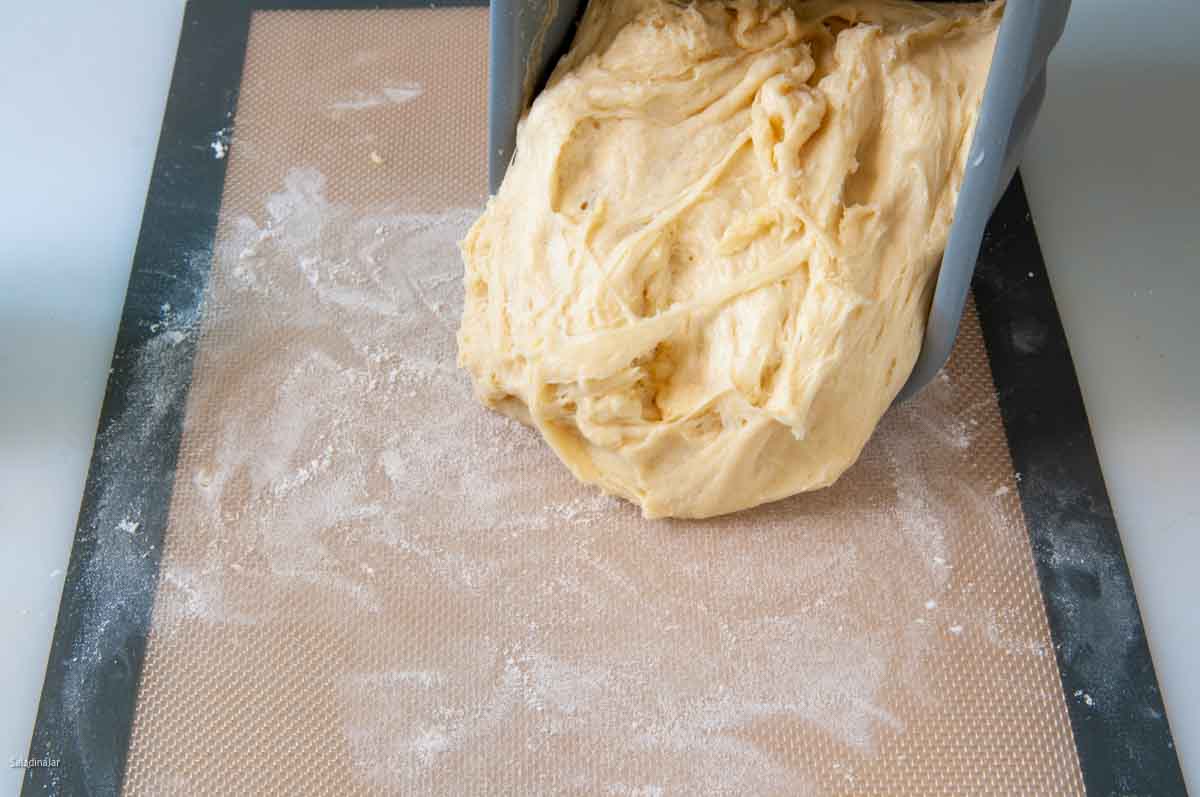Pulling the dough out of the bread machine pan.