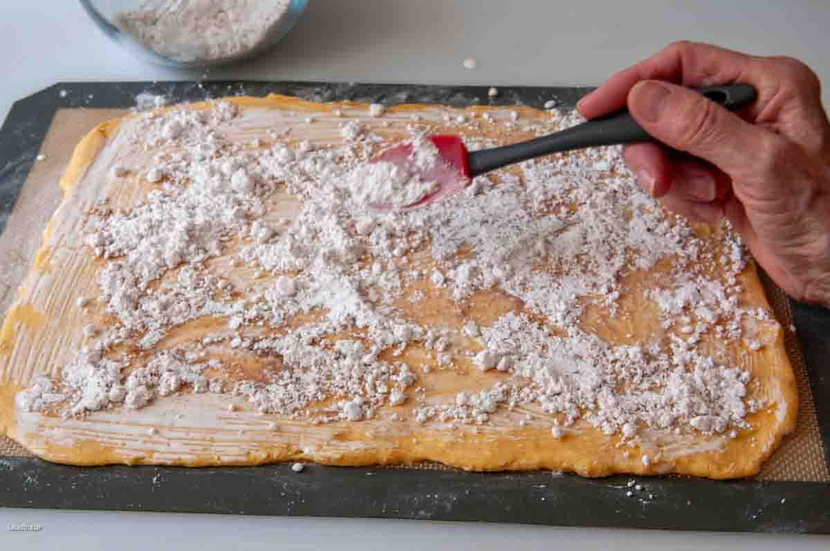 Sprinkling flavored powdered sugar over the dough.