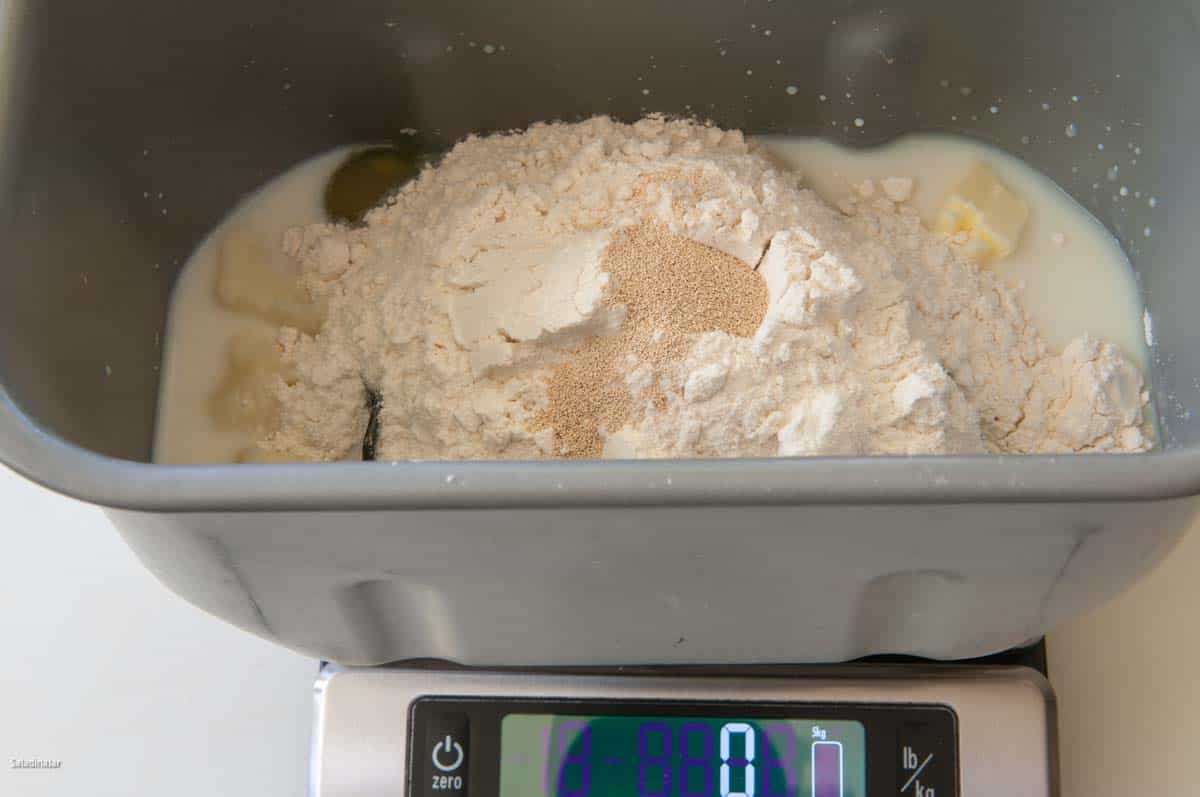 Loading the bread pan with the dough ingredients--shown on a digital scale, the best way to measure flour.