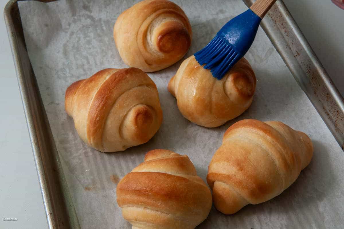 Brushing the rolls with butter after they come out of the oven.