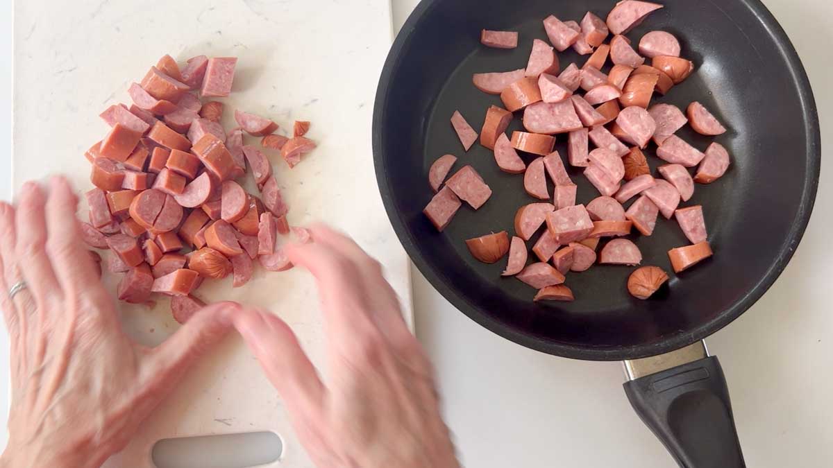 Frying the sausage to melt some of the fat.