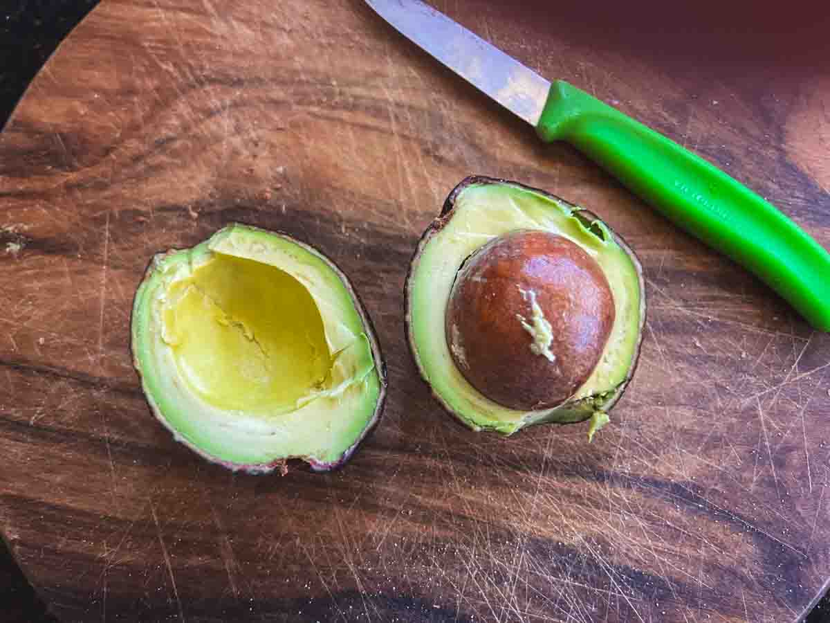 round avocado split in half showing the small amount of flesh inside.
