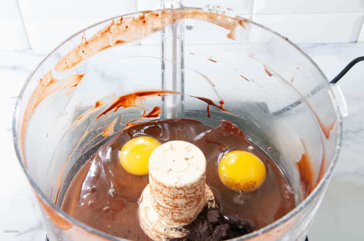 Adding the eggs and cocoa powder to the food processor bowl.