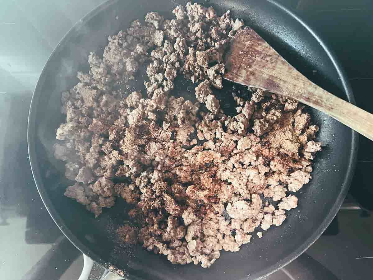 Browning the seasoned ground beef, then adding the taco seasoning.