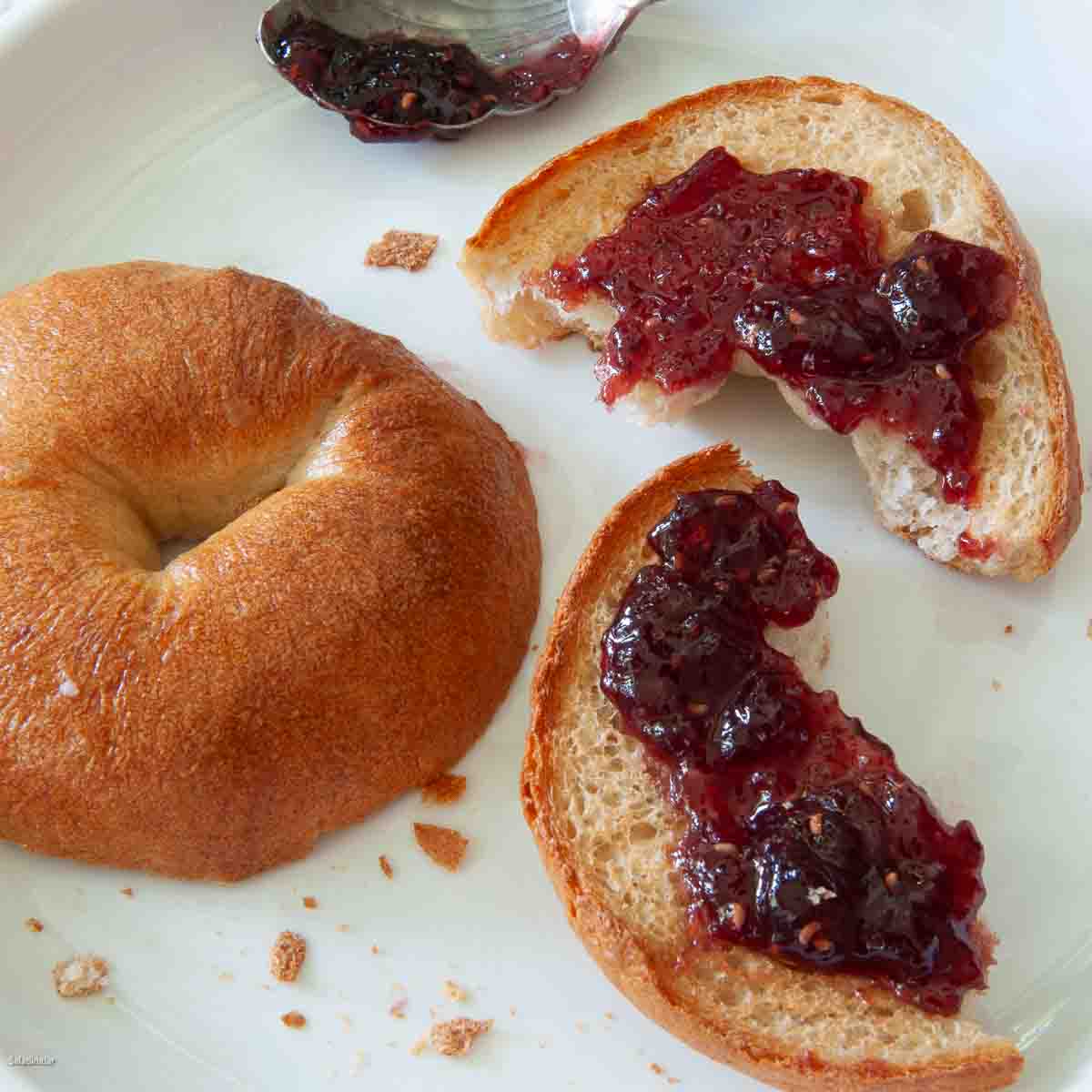 split and toasted bagel with raspberry jelly/