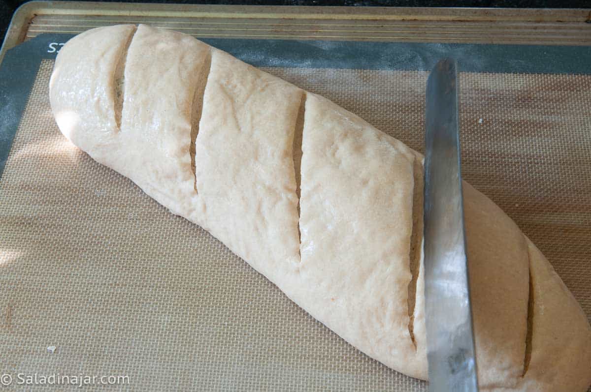 Scoring the loaf with a serrated knife.