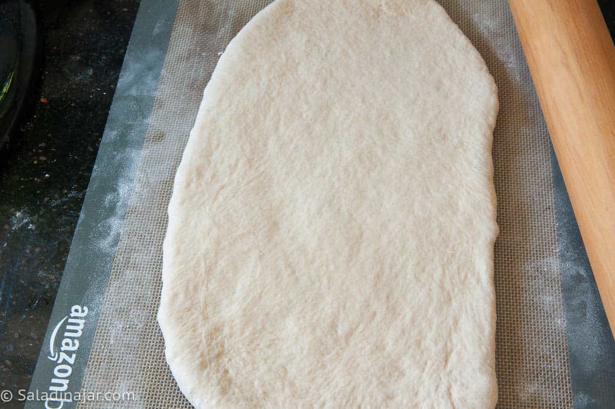 Rolling dough into a long oval shape.