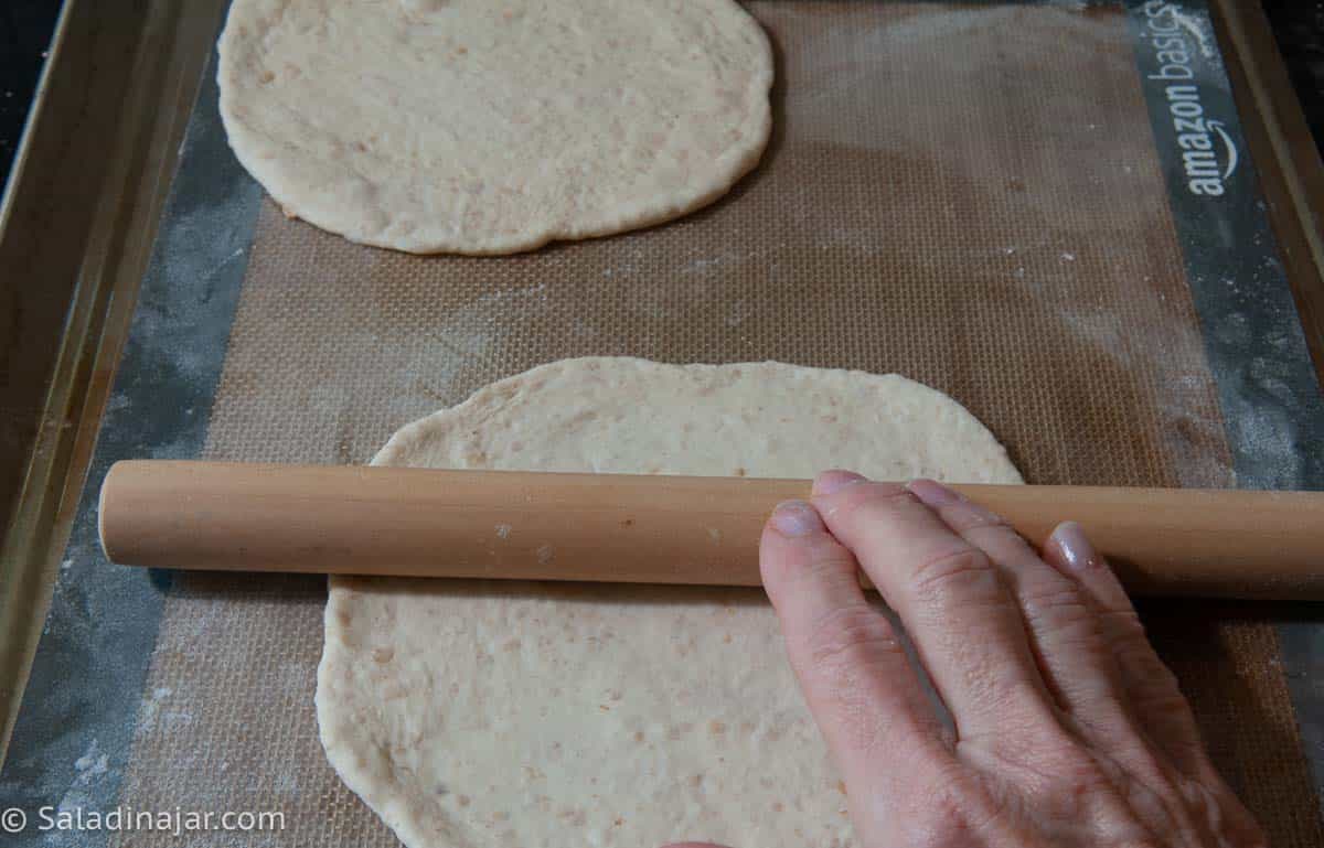 Using a skinny rolling pin to roll each pita to a 7-inch diameter.