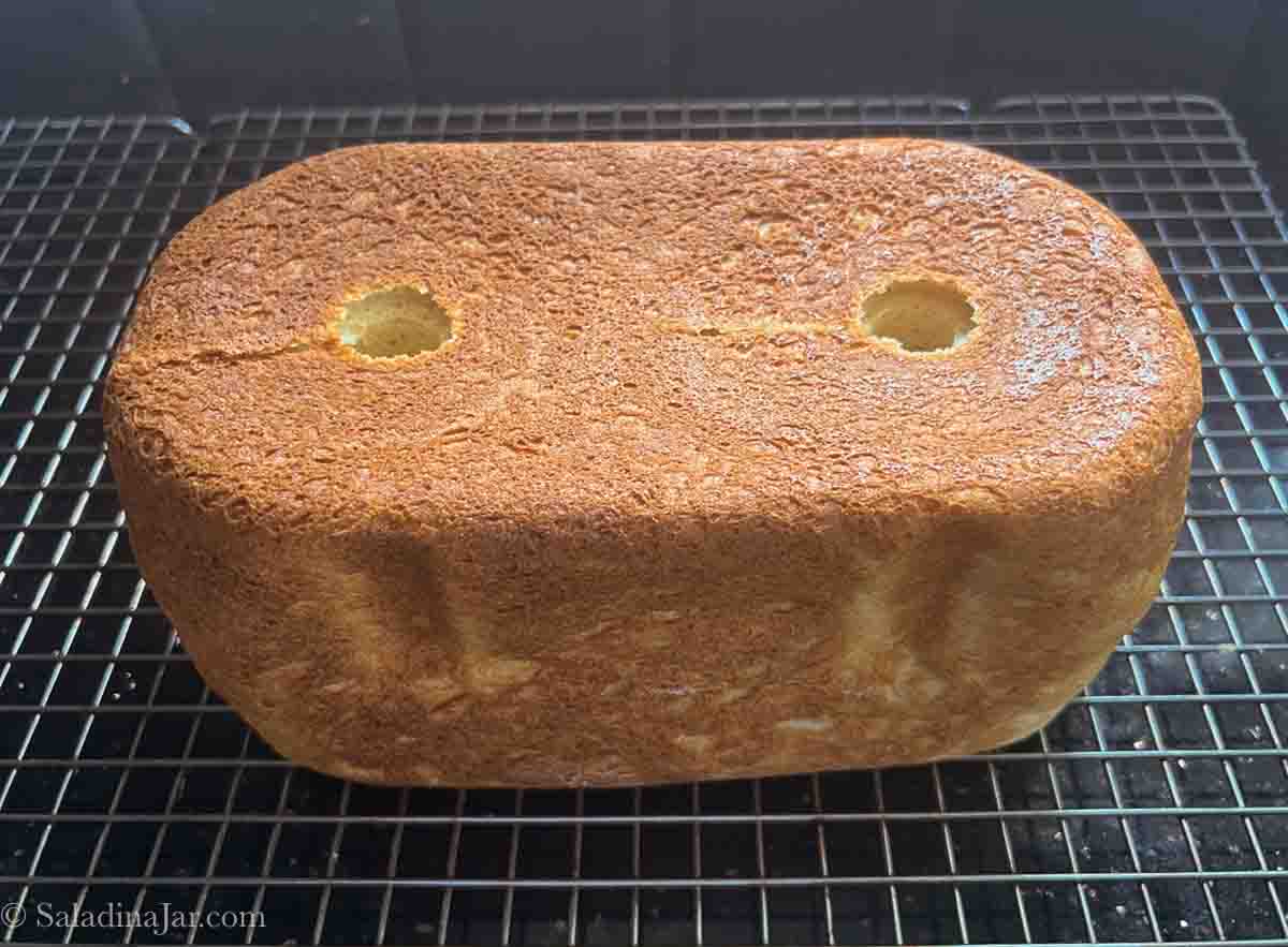 Gluten-free loaf on a rack turned upside down so the holes are obvious.